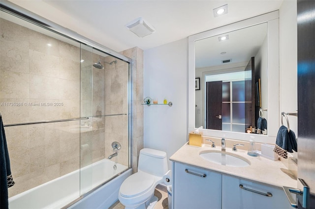 full bathroom featuring toilet, vanity, and shower / bath combination with glass door