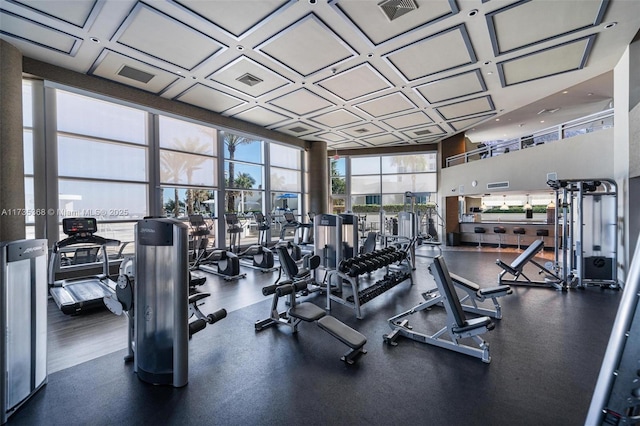 gym with floor to ceiling windows and coffered ceiling