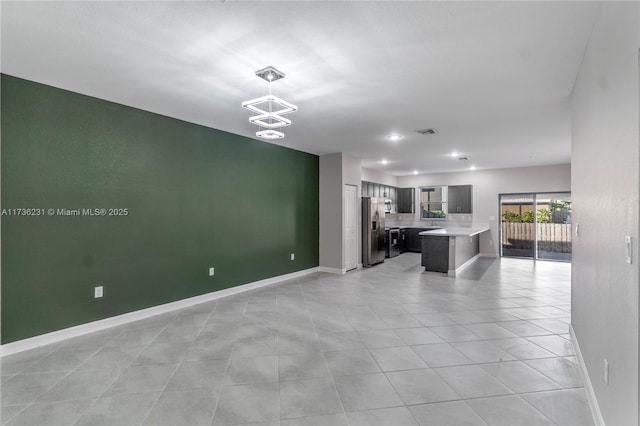 kitchen with a breakfast bar, a center island, light tile patterned floors, stainless steel fridge, and a notable chandelier