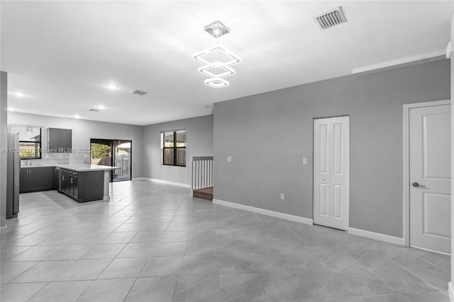 unfurnished living room featuring an inviting chandelier and light tile patterned floors