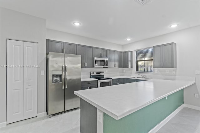 kitchen with sink, light tile patterned floors, appliances with stainless steel finishes, gray cabinetry, and kitchen peninsula