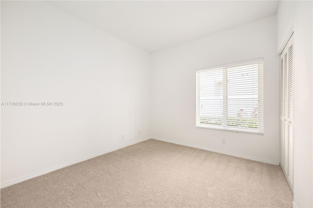 unfurnished bedroom with light colored carpet and a closet