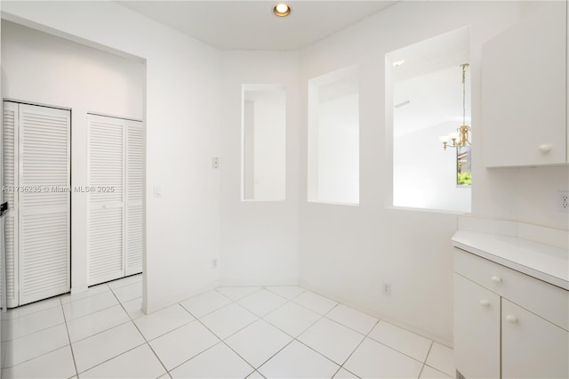 unfurnished dining area with a chandelier and light tile patterned floors