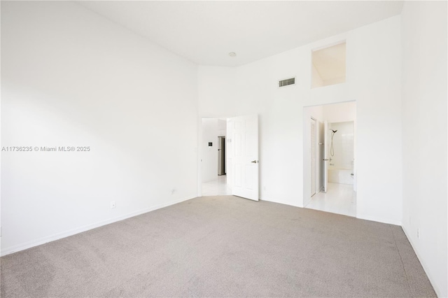 carpeted spare room with a towering ceiling