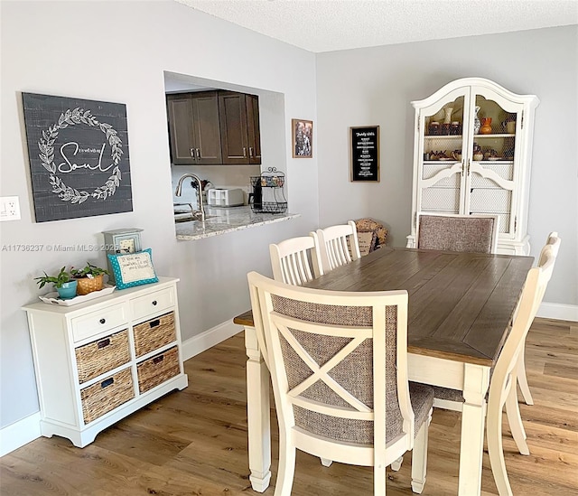 dining area with hardwood / wood-style flooring, sink, and a textured ceiling