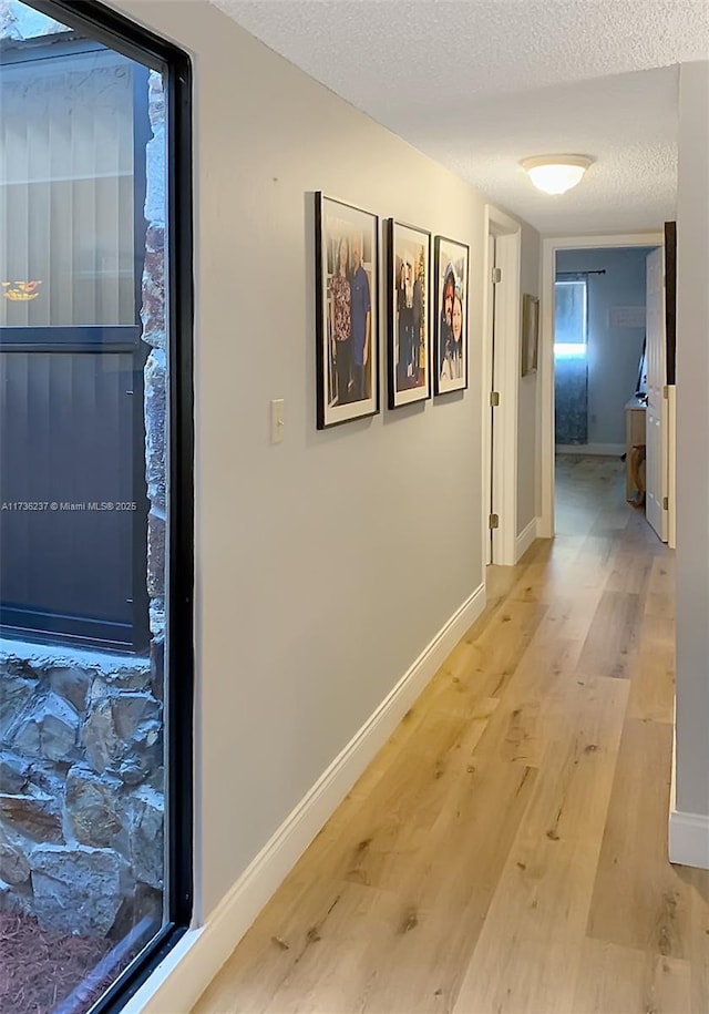 corridor featuring a textured ceiling and light hardwood / wood-style flooring