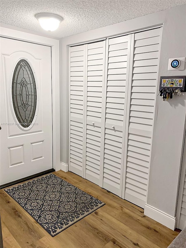 entrance foyer with baseboards, a textured ceiling, and wood finished floors