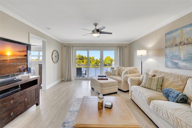 living area featuring a water view, light wood-type flooring, plenty of natural light, and crown molding