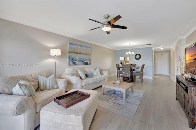 living area featuring ceiling fan with notable chandelier, ornamental molding, baseboards, and light wood-style floors