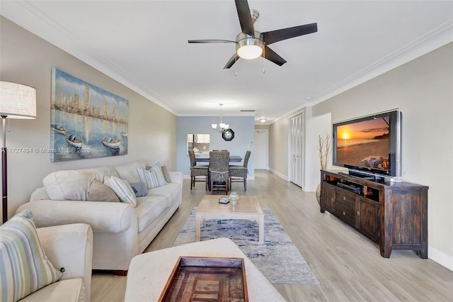 living room featuring light wood-style floors, ornamental molding, baseboards, and ceiling fan with notable chandelier