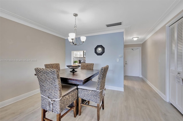 dining room with light wood-style floors, baseboards, visible vents, and ornamental molding