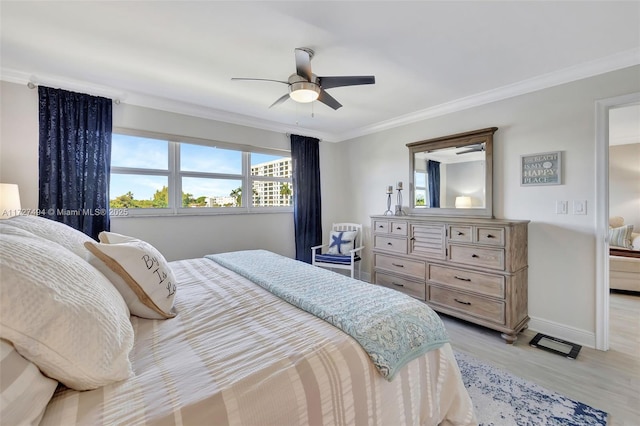 bedroom with ornamental molding, light wood-type flooring, a ceiling fan, and baseboards