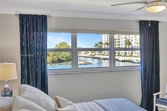 bedroom with ornamental molding, a water view, and a ceiling fan