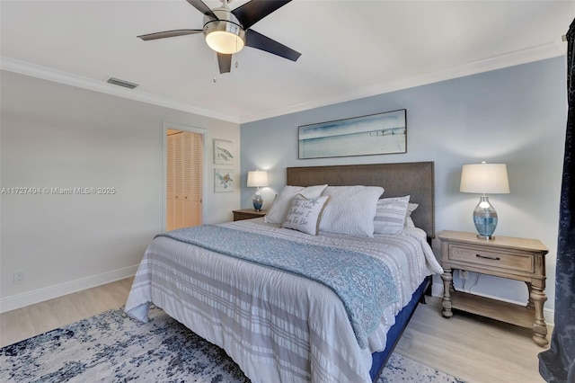 bedroom with light wood-style floors, visible vents, crown molding, and baseboards