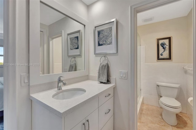 bathroom featuring tile patterned flooring, toilet, vanity, tile walls, and a stall shower