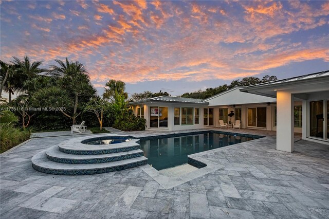 16141 W Troon Cir, Miami Lakes, FL 33014 - pool at dusk featuring a patio, a ceiling fan, and a pool with connected hot tub