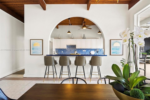 kitchen with backsplash, beamed ceiling, wooden ceiling, and white cabinets