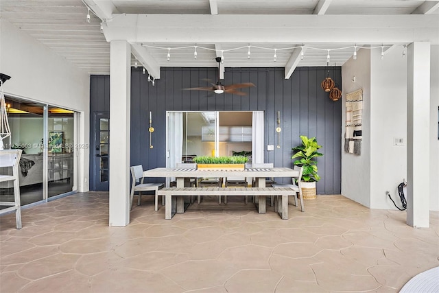 dining area featuring ceiling fan, wooden walls, and beamed ceiling