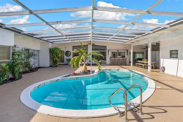 view of swimming pool with a lanai, a patio area, ceiling fan, and exterior bar