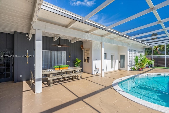 view of swimming pool with ceiling fan, glass enclosure, and a patio area