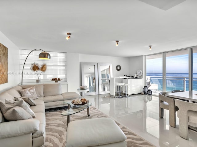 living room featuring floor to ceiling windows, a water view, and light tile patterned flooring