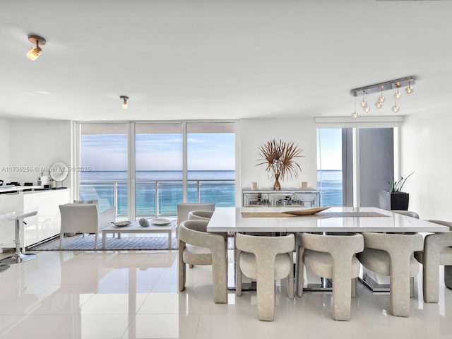 tiled dining area with expansive windows, a water view, a wealth of natural light, and track lighting