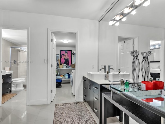 bathroom featuring tile patterned flooring, vanity, a shower, separate washer and dryer, and toilet