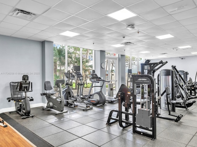 gym featuring expansive windows and a drop ceiling