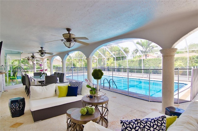 view of swimming pool featuring an outdoor living space, a patio area, ceiling fan, and glass enclosure