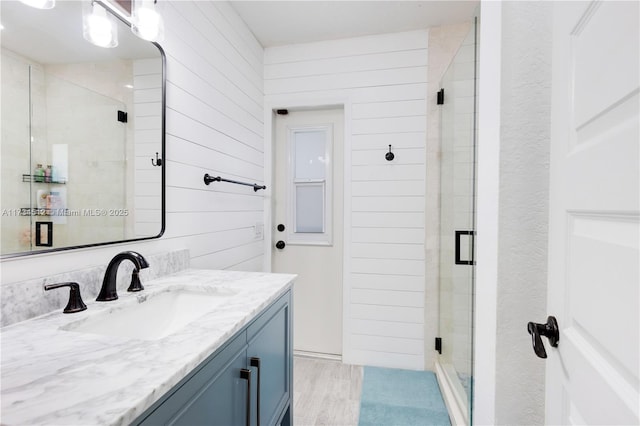 bathroom with vanity, wooden walls, and a shower with door