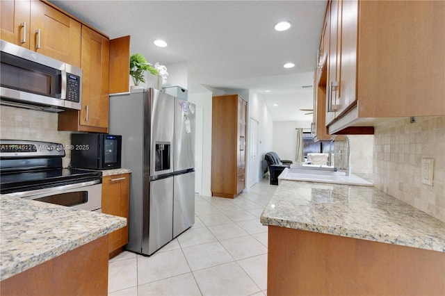 kitchen featuring stainless steel appliances, tasteful backsplash, light stone countertops, and light tile patterned floors