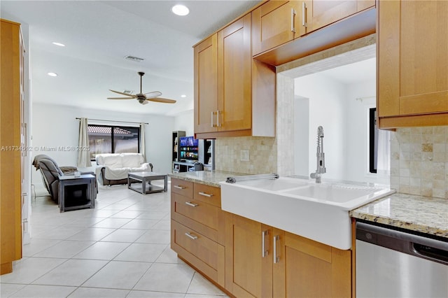 kitchen with light stone counters, light tile patterned floors, stainless steel dishwasher, ceiling fan, and decorative backsplash