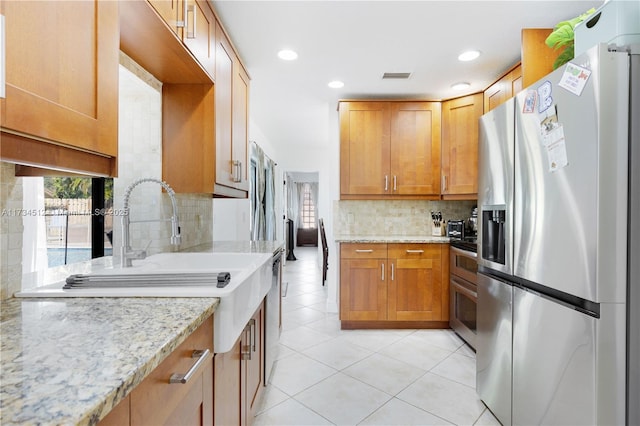 kitchen with stainless steel appliances, light stone countertops, light tile patterned floors, and backsplash