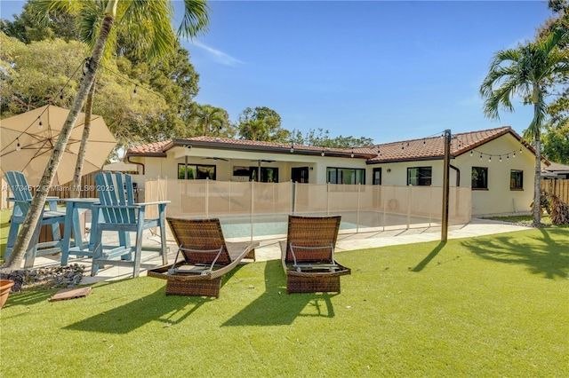 rear view of property featuring a pool, a lawn, and a patio