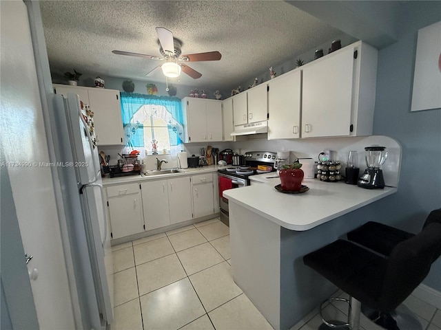 kitchen featuring electric stove, freestanding refrigerator, light tile patterned flooring, a peninsula, and under cabinet range hood