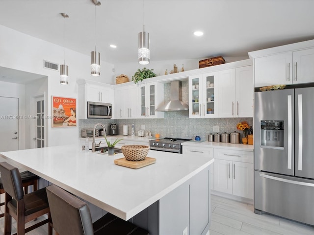 kitchen featuring wall chimney exhaust hood, white cabinetry, stainless steel appliances, and sink