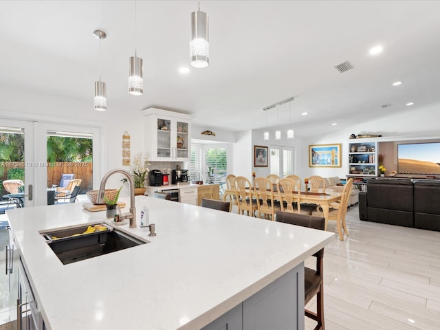 kitchen featuring white cabinetry, sink, hanging light fixtures, and french doors