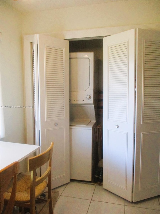 laundry area with light tile patterned flooring and stacked washing maching and dryer