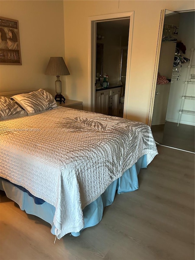 bedroom featuring hardwood / wood-style floors, ensuite bath, a walk in closet, and a closet