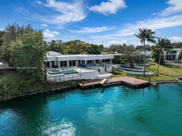 rear view of house featuring a hot tub and a water view