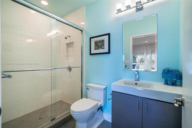 bathroom featuring a shower with door, vanity, and toilet