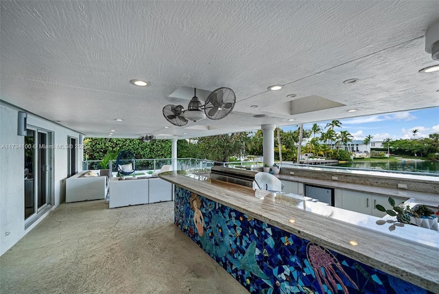 view of patio featuring a bar, ceiling fan, and a water view