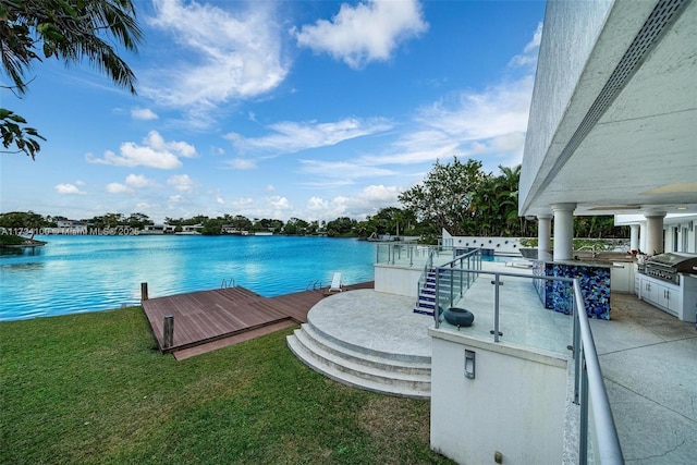 exterior space with a water view, an outdoor kitchen, area for grilling, and a lawn