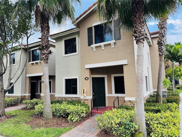 view of property featuring stucco siding and stone siding