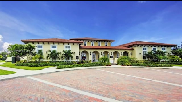 view of front of house featuring stucco siding, a tile roof, and uncovered parking