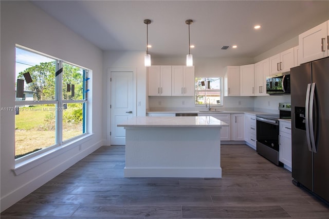 kitchen with sink, appliances with stainless steel finishes, white cabinetry, a center island, and decorative light fixtures