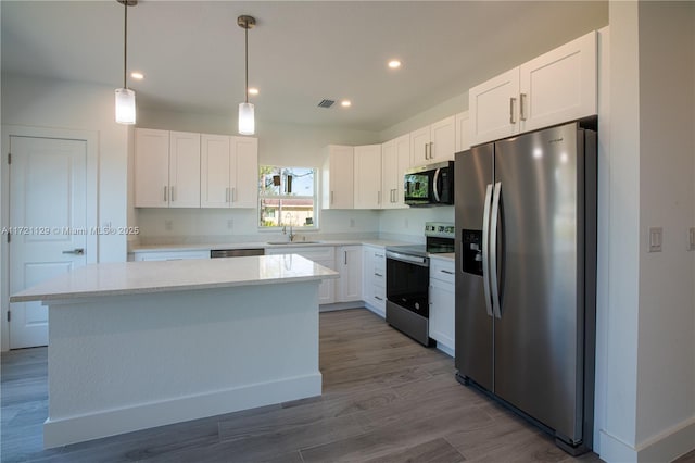 kitchen featuring white cabinetry, stainless steel appliances, a kitchen island, and hanging light fixtures