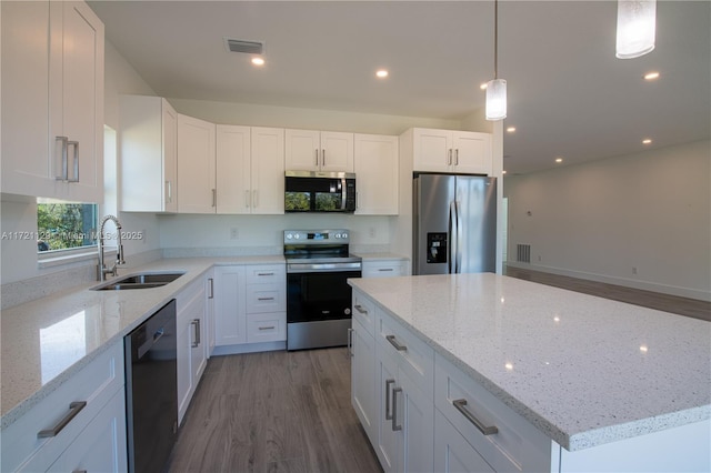 kitchen with sink, light stone counters, pendant lighting, stainless steel appliances, and white cabinets