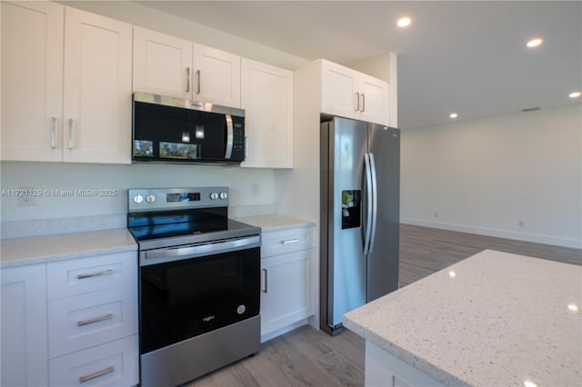 kitchen featuring white cabinetry, stainless steel appliances, light stone counters, and light wood-type flooring