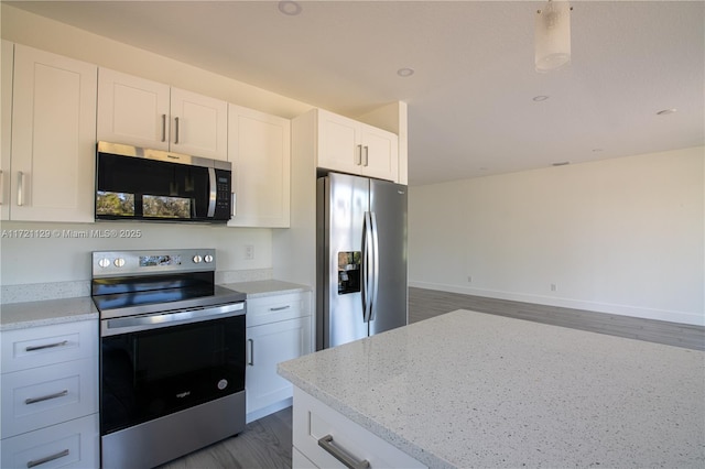 kitchen with white cabinetry, stainless steel appliances, dark hardwood / wood-style floors, and light stone countertops